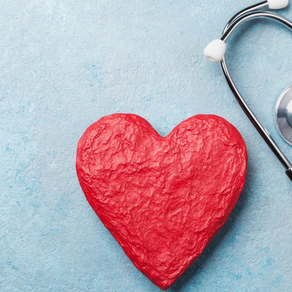 Red heart shape and medical stethoscope on blue background top view. Health care, medicare and cardiology concept.