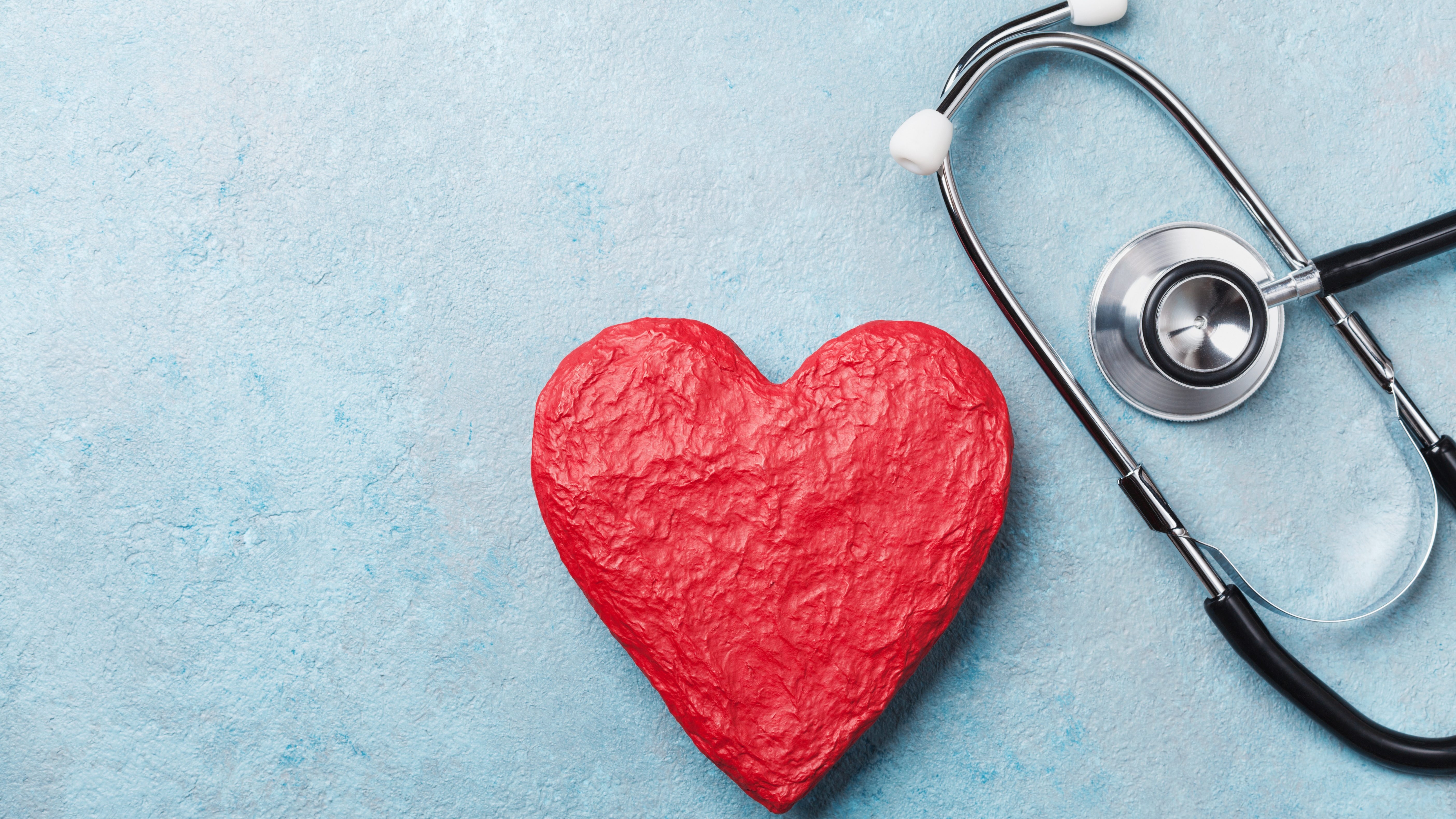 Red heart shape and medical stethoscope on blue background top view. Health care, medicare and cardiology concept.