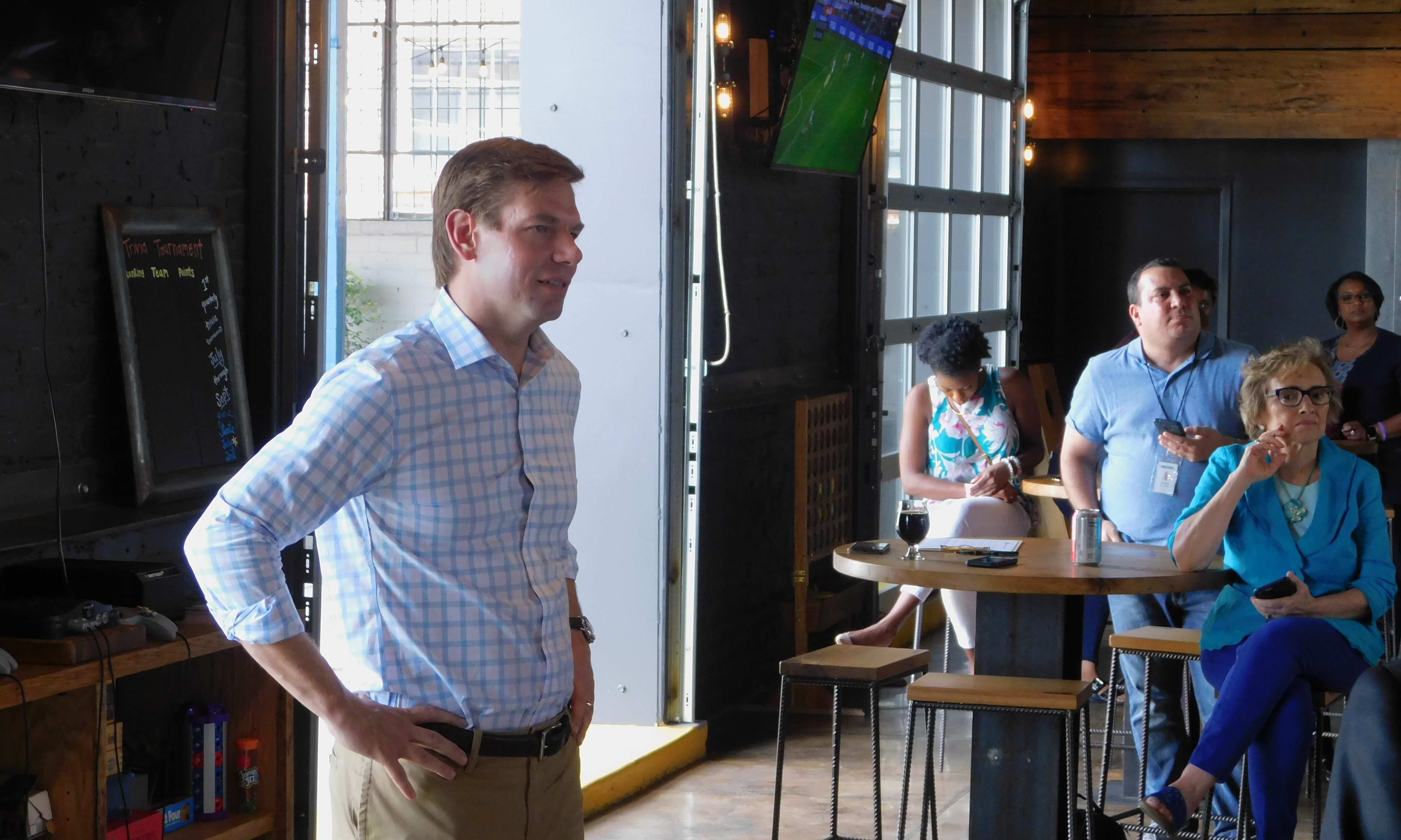 Eric Swalwell stands by a window before a crowd