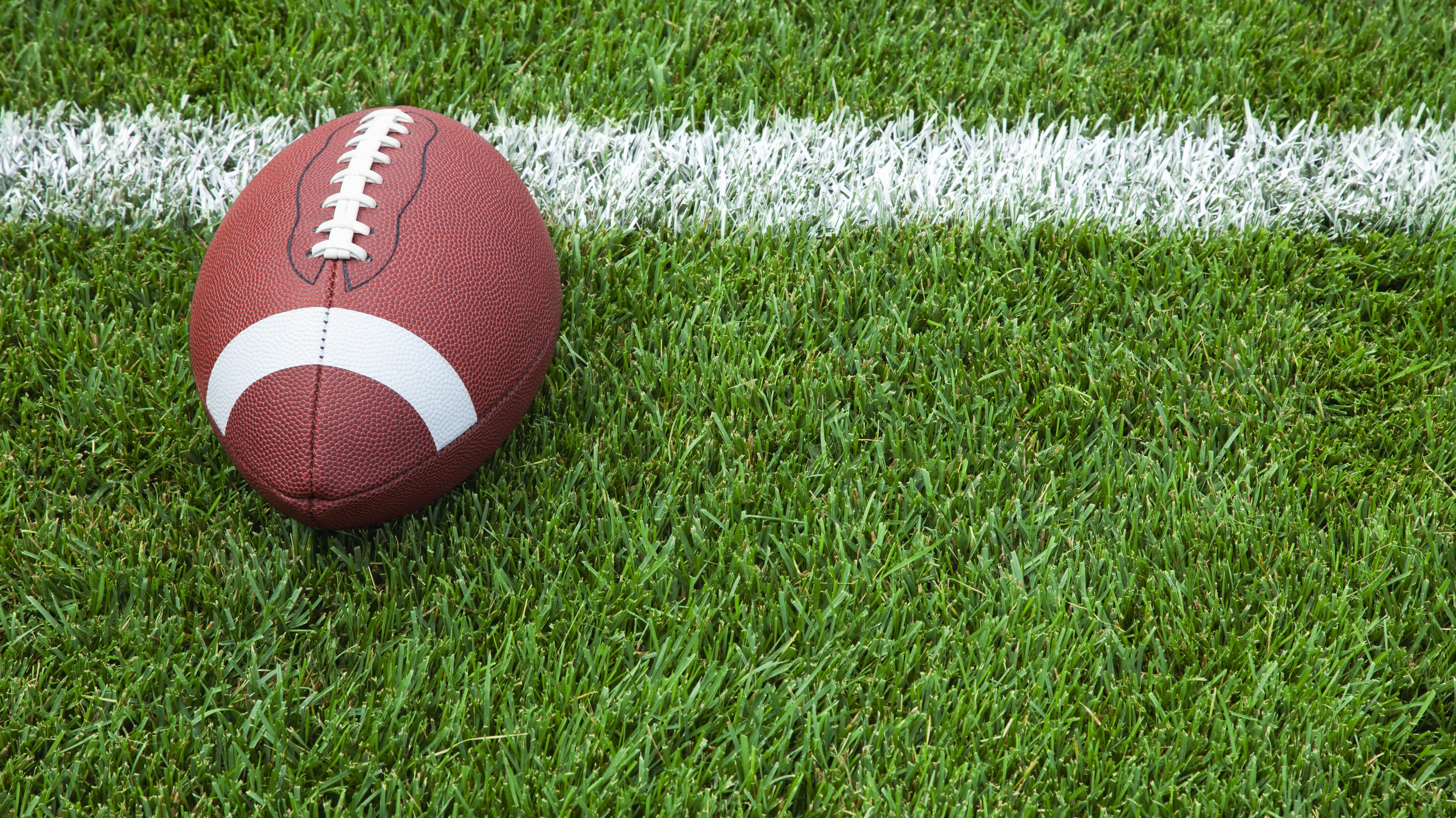 A college football at the goal line on a grass field