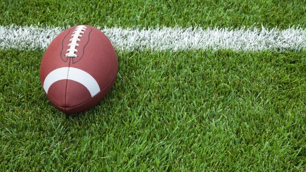 A college football at the goal line on a grass field