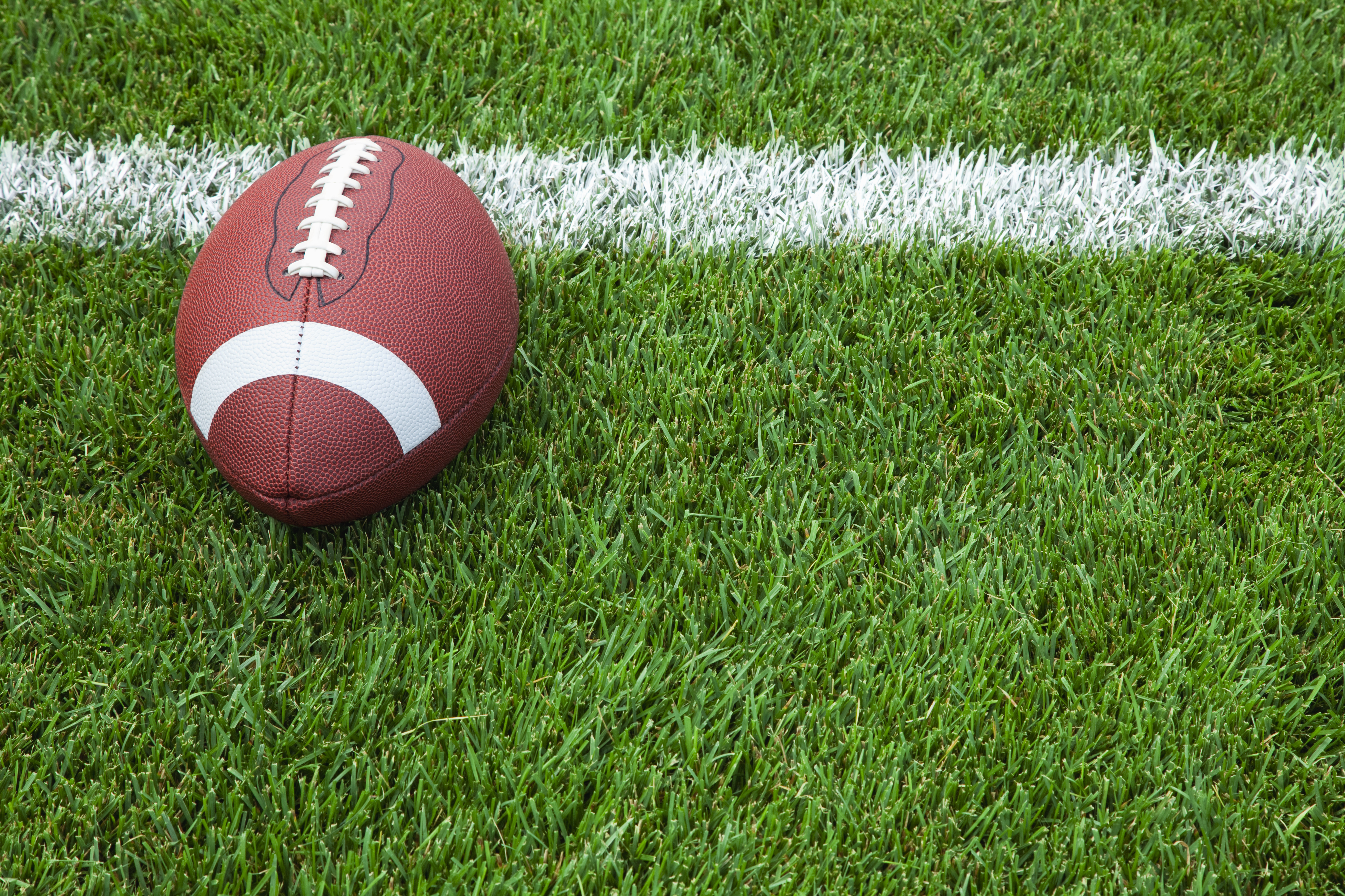 A college football at the goal line on a grass field