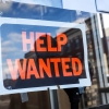 Reflection of a man looking at a help wanted sign in a business window, economy concept