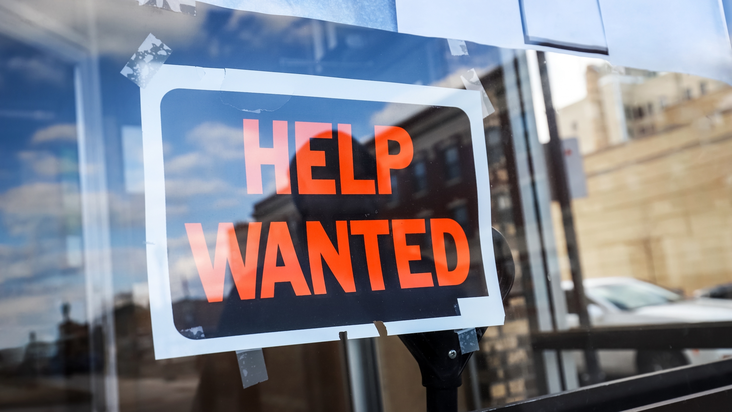 Reflection of a man looking at a help wanted sign in a business window, economy concept