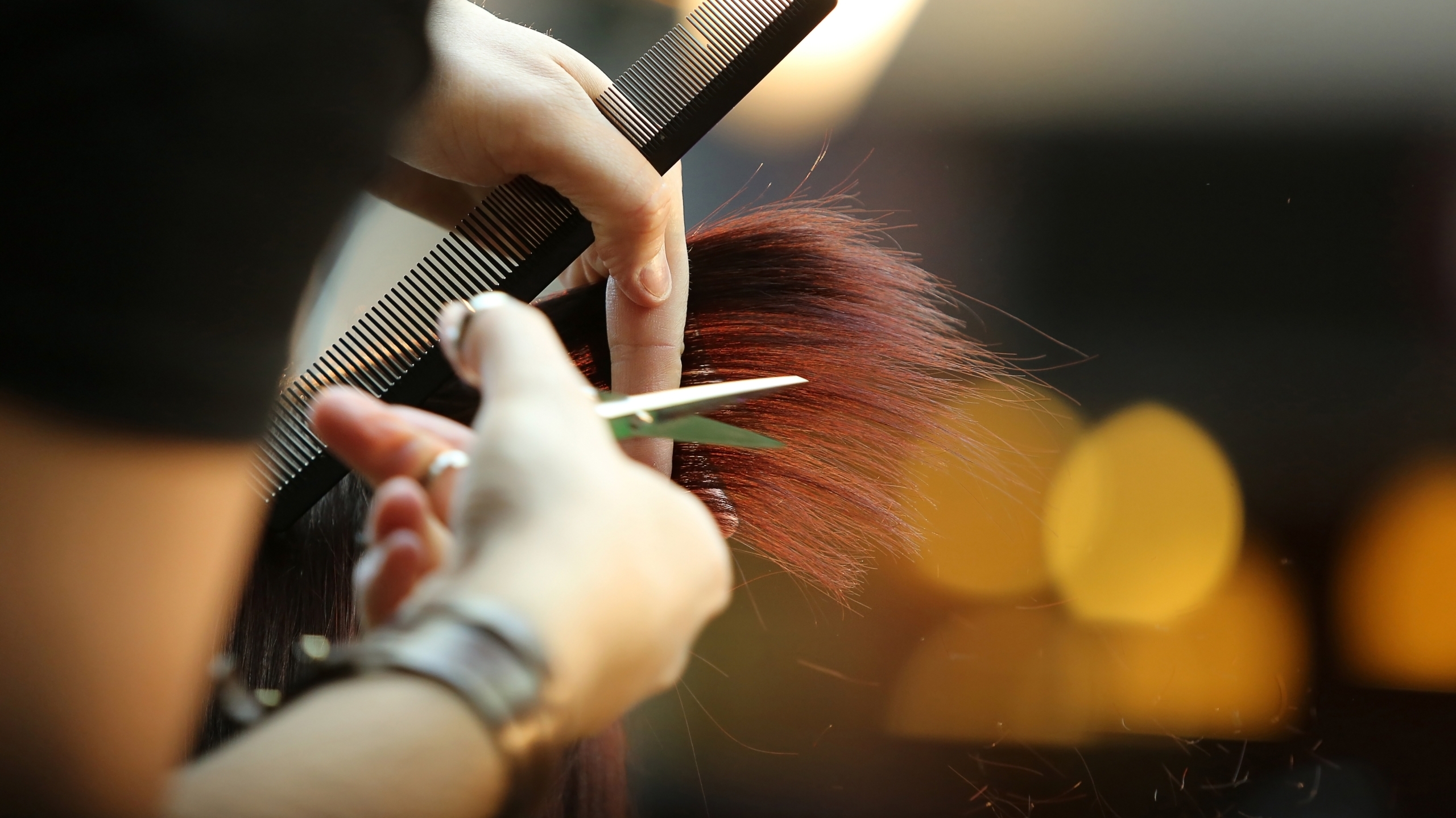 Hairdresser trimming brown hair with scissors