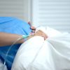 Pregnant woman holding blanket, feeling abdominal pain, risk of miscarriage