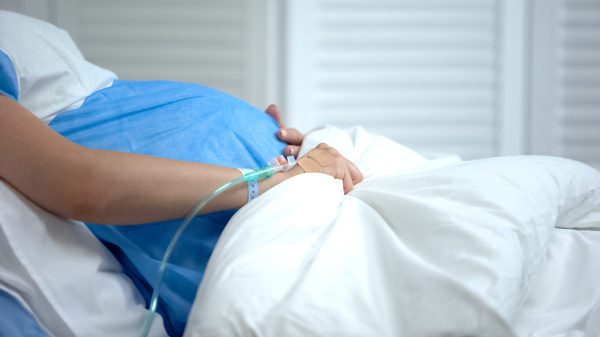 Pregnant woman holding blanket, feeling abdominal pain, risk of miscarriage