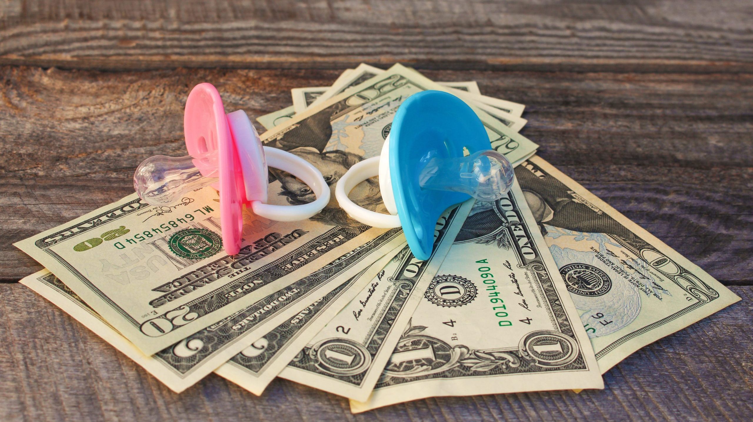 Blue and pink pacifiers on the background of money.