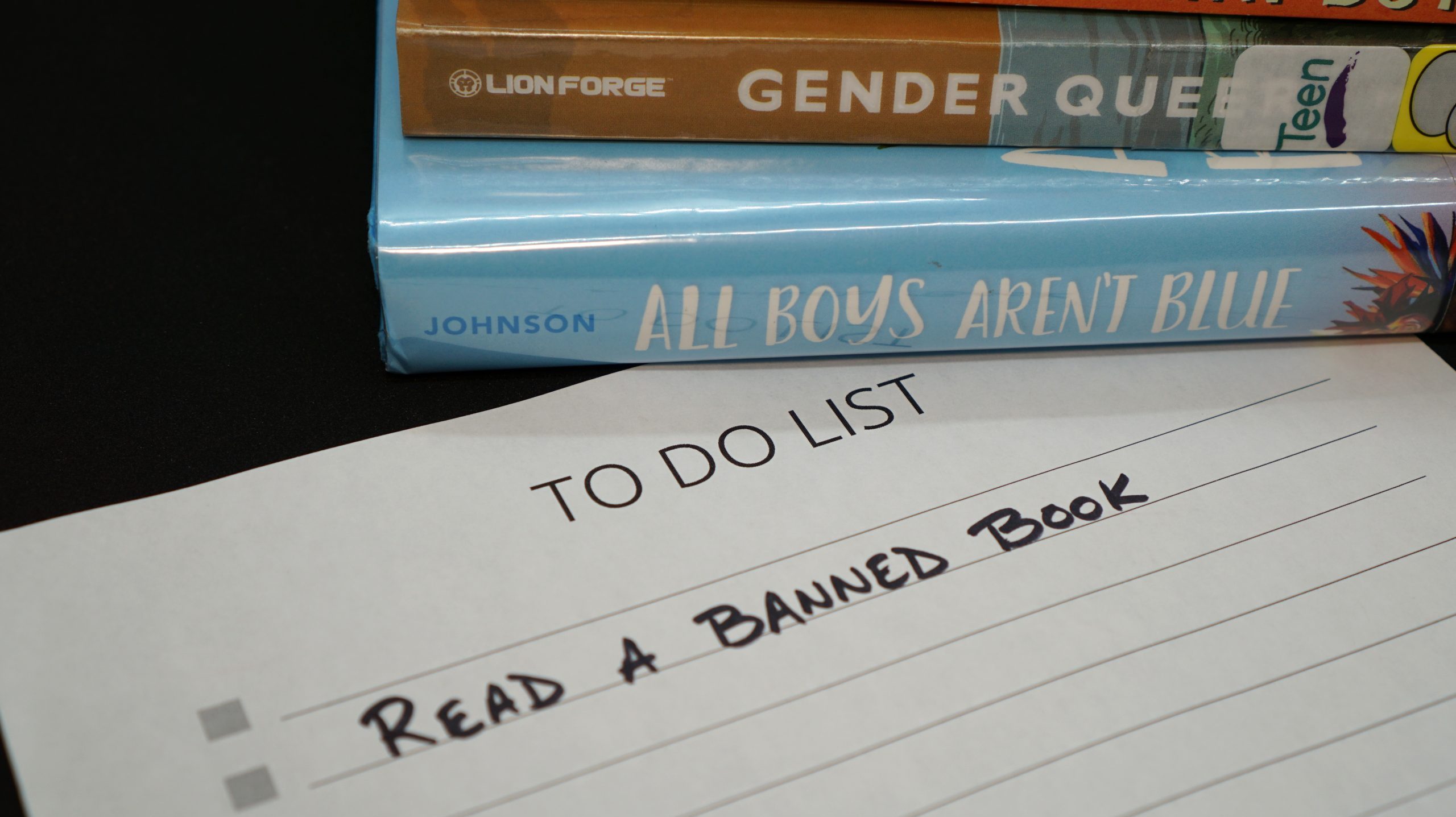 To do list reminder to read a banned book, along with a pile of books frequently on censorship lists.