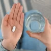 Young woman with abortion pill and glass of water, top view