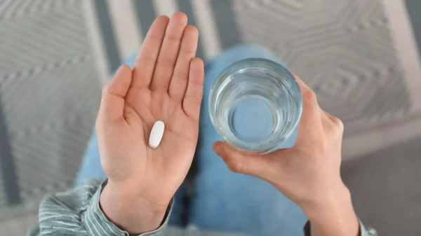 Young woman with abortion pill and glass of water, top view