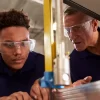 Carpenter Training Male Apprentice To Use Mechanized Saw
