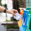 Closeup portrait woman hand throwing crumpled paper in recycling bin.
