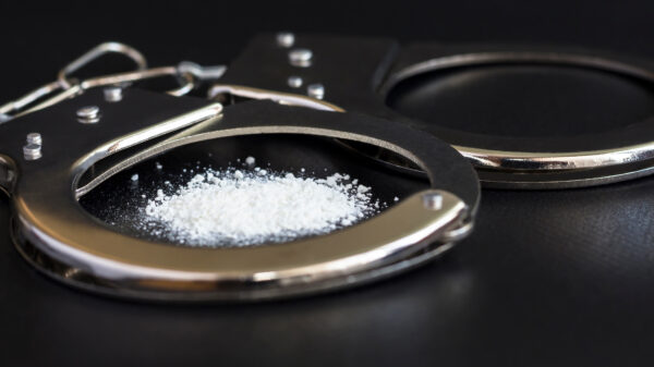 handcuffs and drugs on black table. concept arrest of drug, addiction