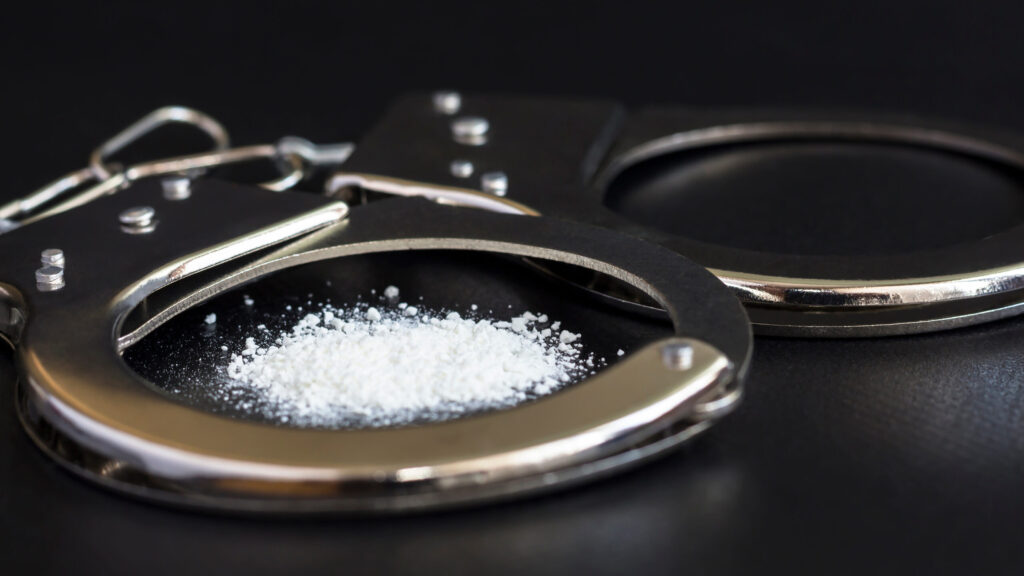 handcuffs and drugs on black table. concept arrest of drug, addiction