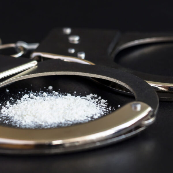 handcuffs and drugs on black table. concept arrest of drug, addiction