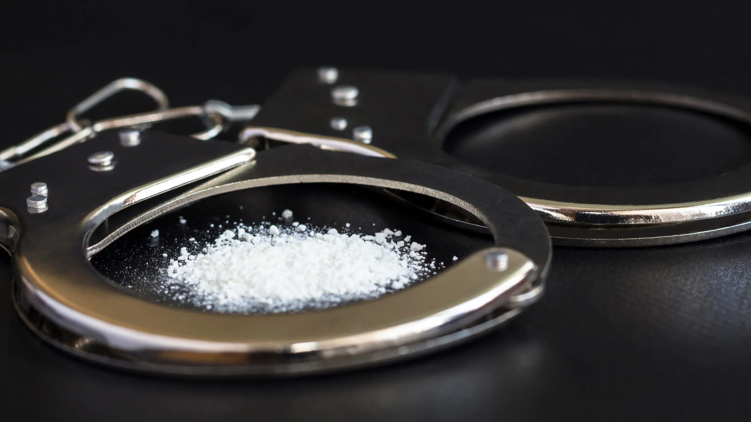 handcuffs and drugs on black table. concept arrest of drug, addiction