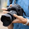 Young male photographer with camera outdoors, closeup