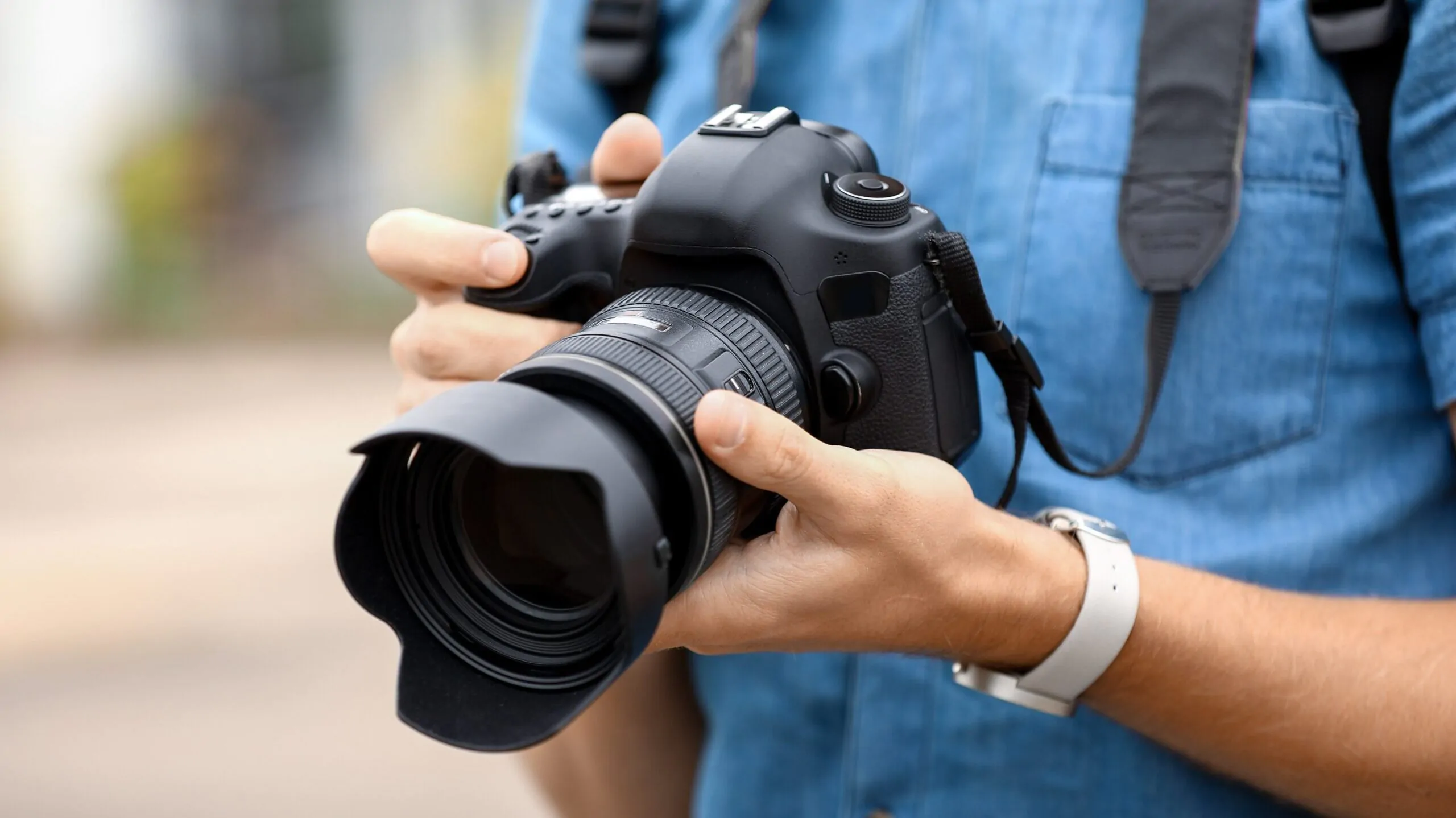 Young male photographer with camera outdoors, closeup